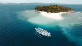 Aerial drone view of the Seatours 90ft expedition boat anchored off a white-sand tropical island on the private 3D2N Palawan charter route, Palawan