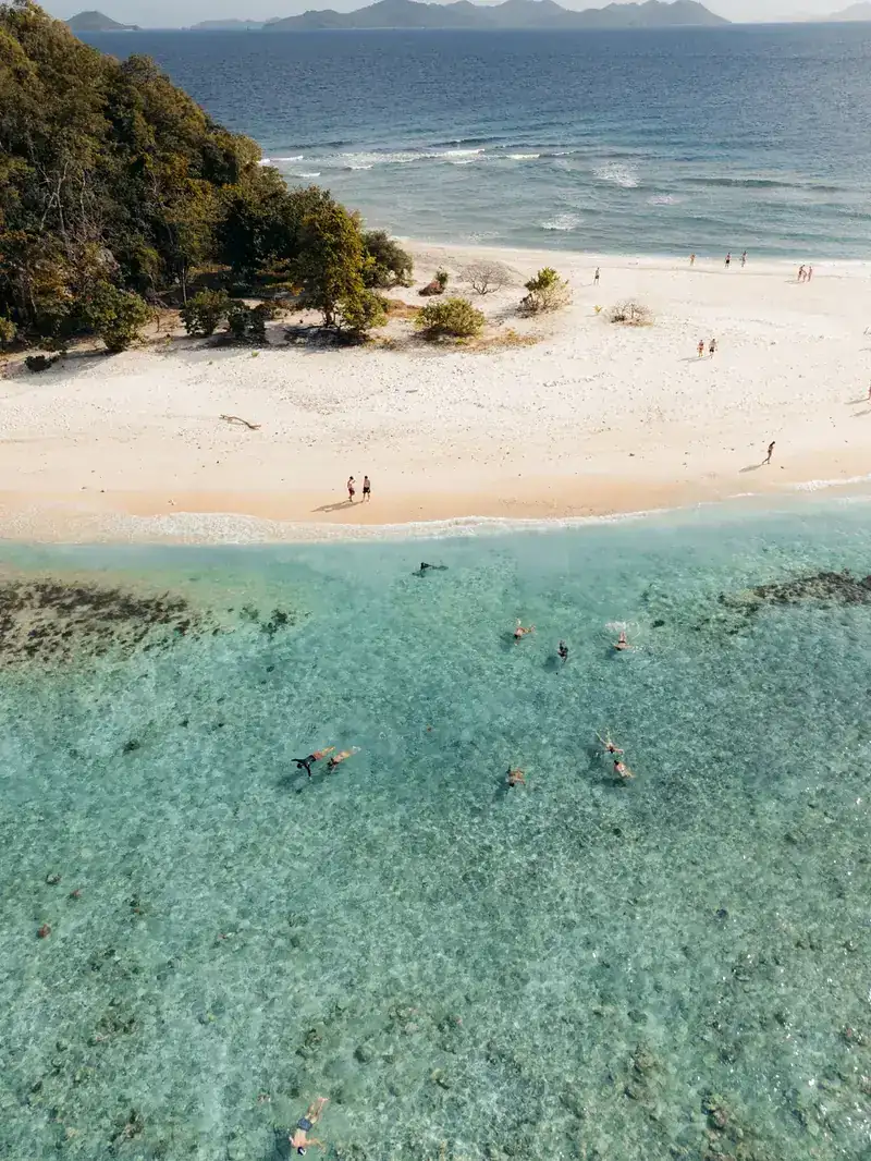 Aerial view of snorkelers above a Linapacan reef in calm clear water