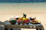 Fresh grilled seafood and tropical fruit lunch served on a white-sand beach during a Seatours El Nido speedboat day tour